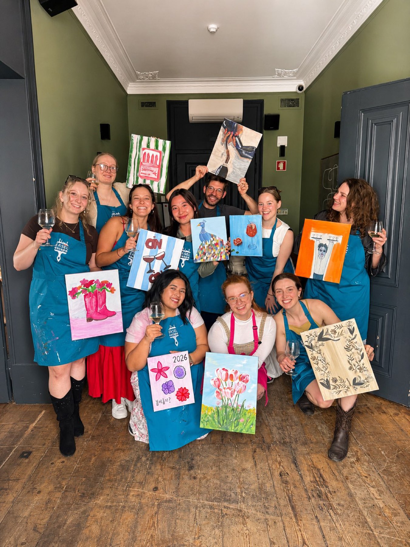 A hen party holding their canvases in a green room
