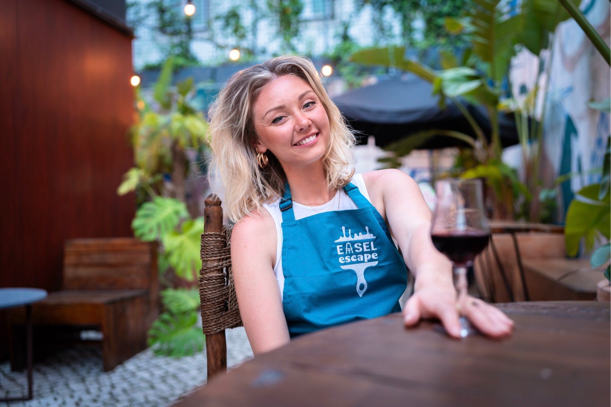 Emma Stewart, founder of Easel Escape, in an Easel Escape apron with a glass of red wine