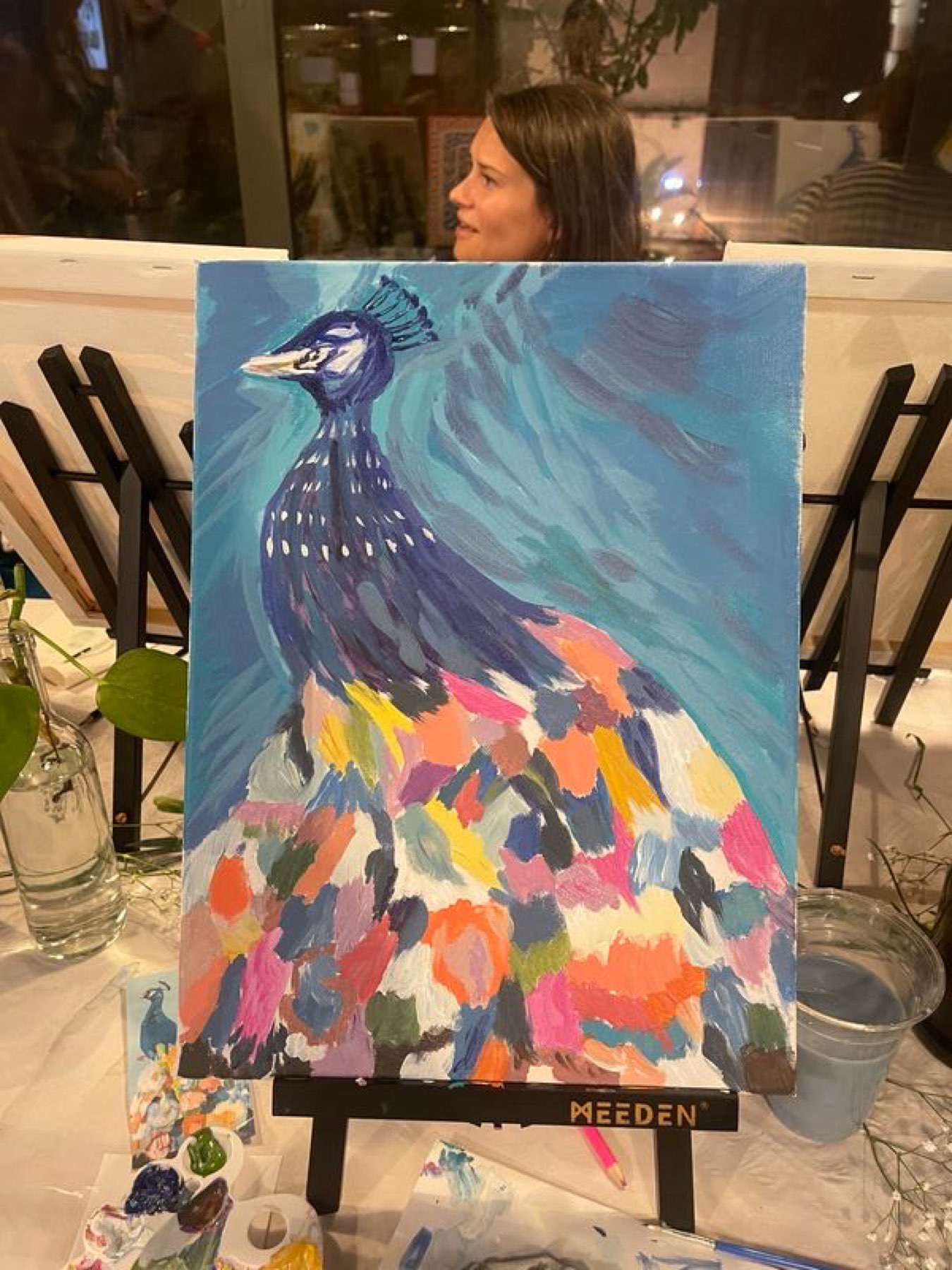 A peacock painting on the easel