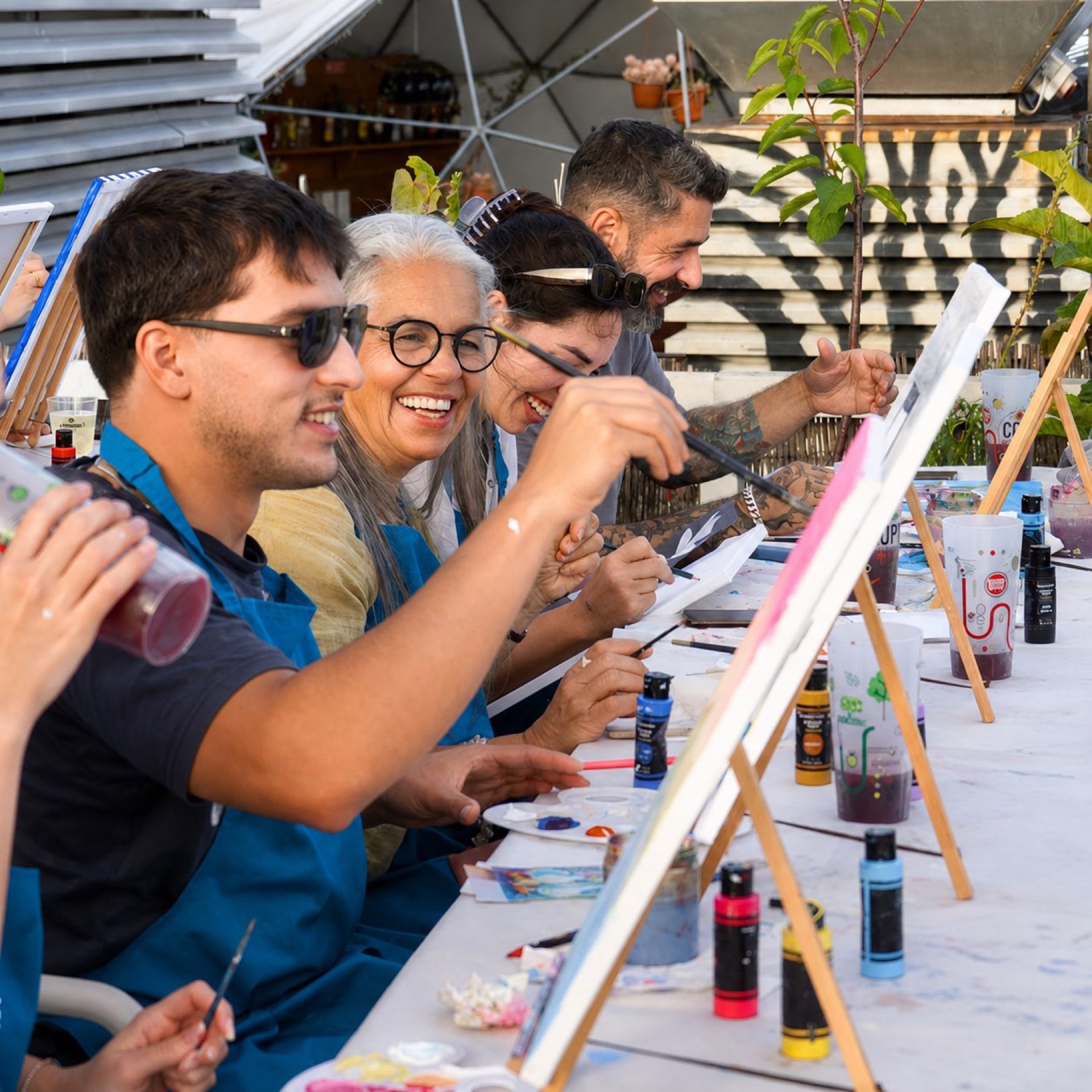 A long table of painters at golden hour on a Lisbon rooftop