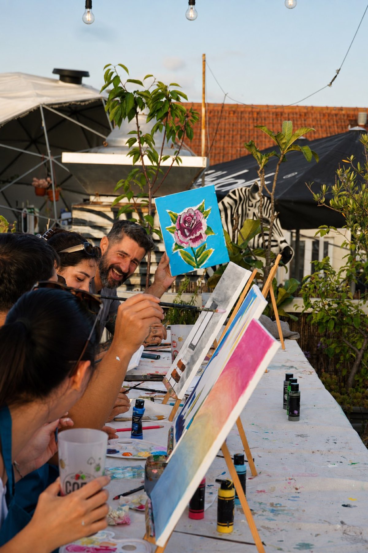 A guest holding up her rose canvas at sunset